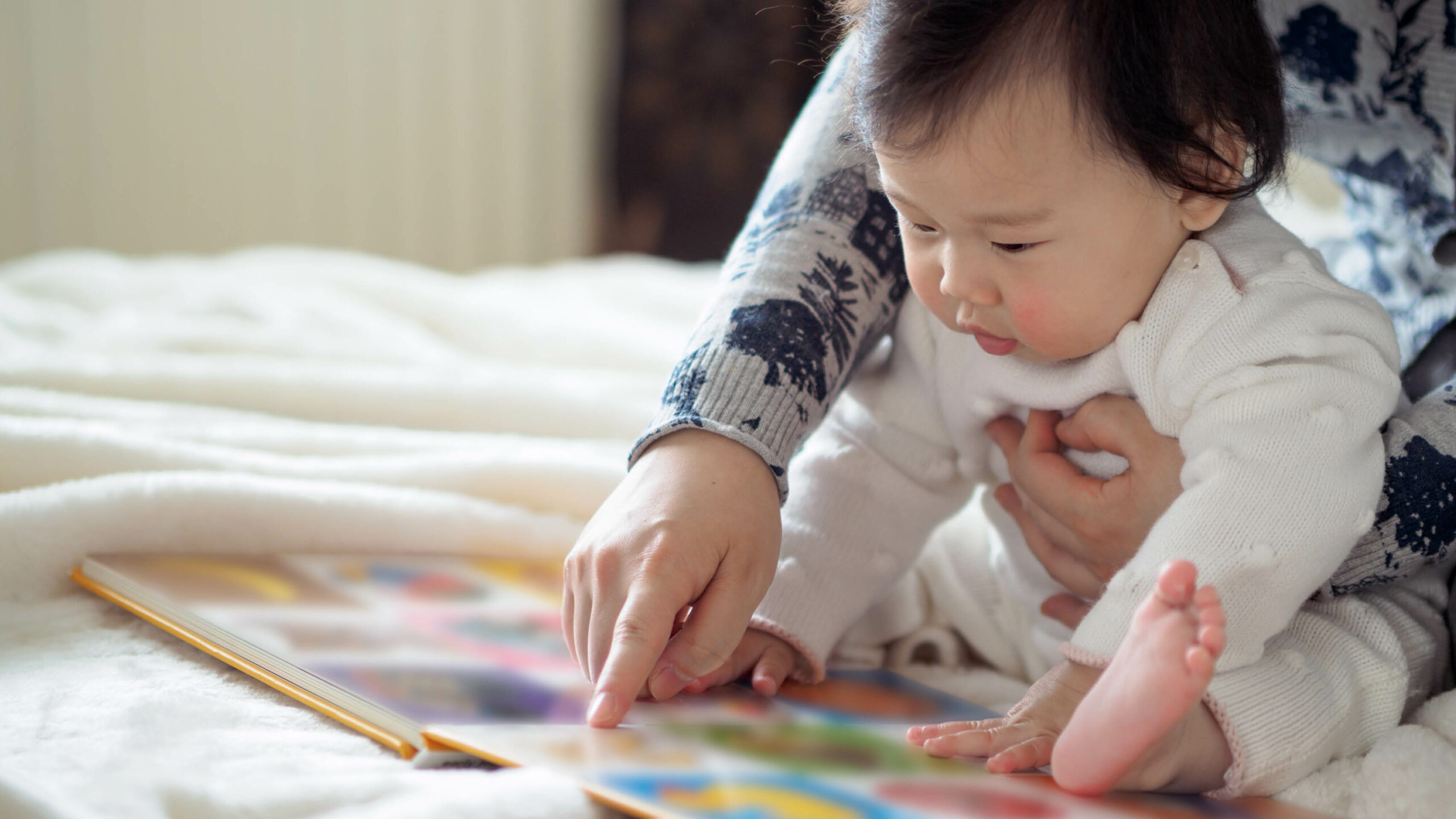 Baby girl reading book with mom stock photo